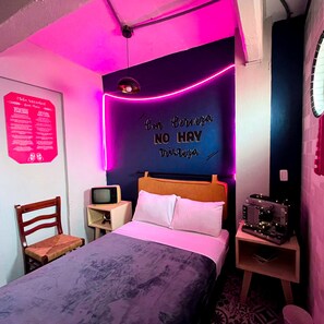 A bedroom with a bed, a wooden headboard, a television on a small table, and a neon sign on the wall. - Mala Vecindad Centro Historico (Mexico City)
