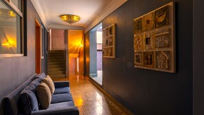 A hallway with a blue sofa, a chandelier, and artwork on the walls. - Mala Vecindad Centro Historico (Mexico City)