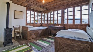 Una habitación rústica de madera con dos camas, una silla, un tocador y un ventanal grande con vista a un cuerpo de agua.