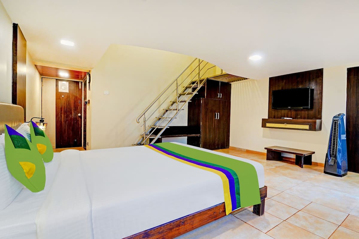 Quarto de hotel com cama, escada, televisão e aquecedor.
