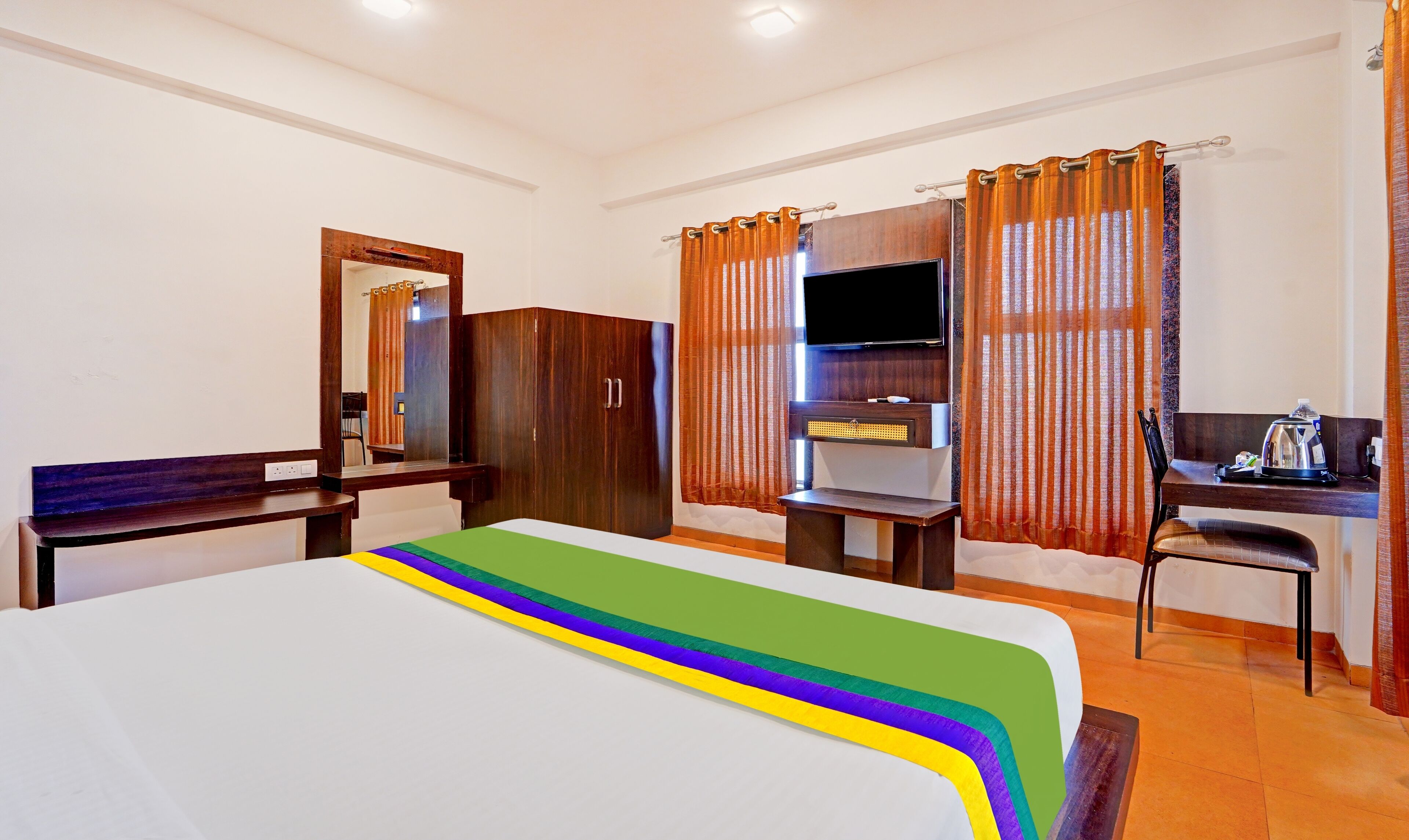 A hotel room with a bed, a desk, a TV, and a wardrobe.