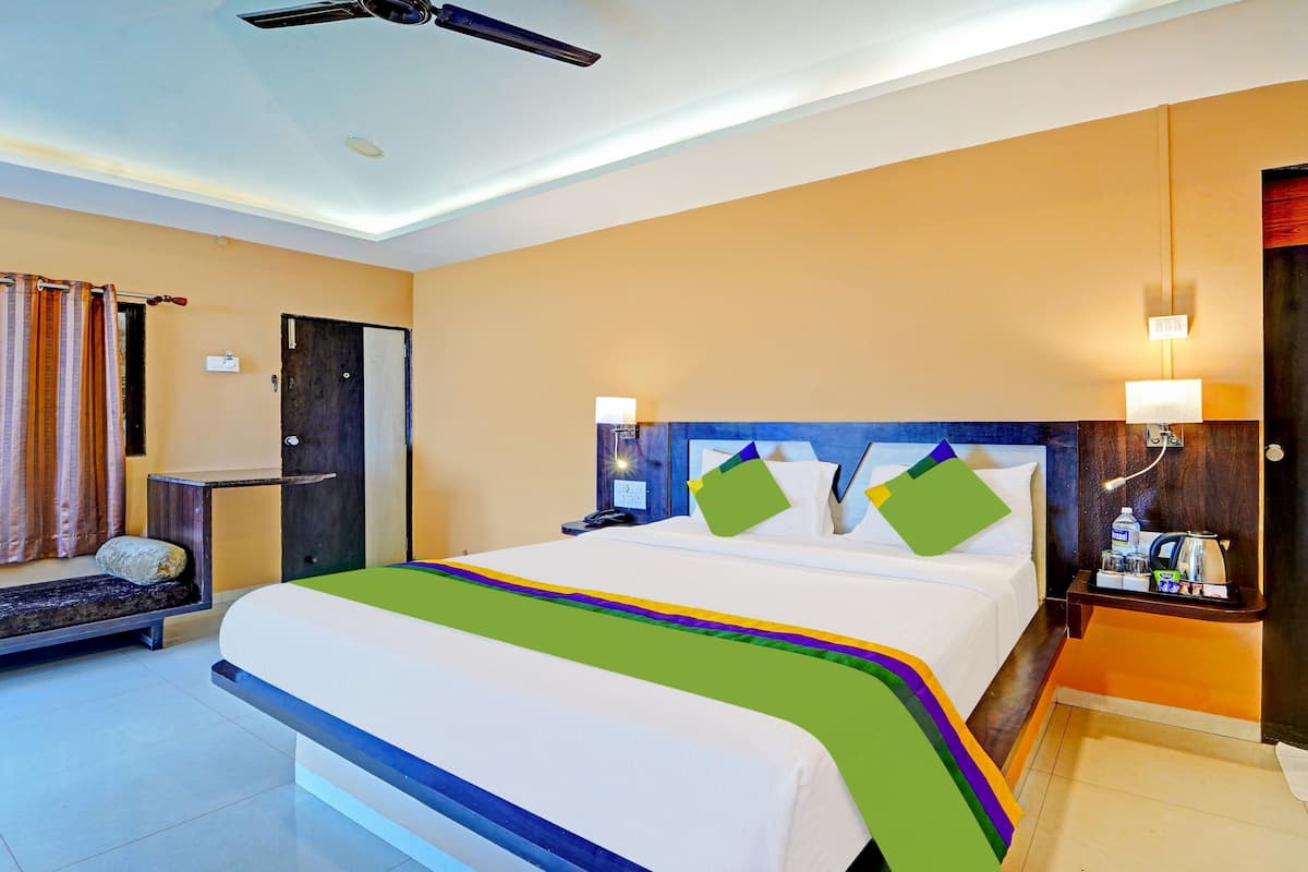 Quarto de hotel com cama, mesa de cabeceira, abajur e vista para o exterior.