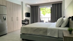 Ett modernt hotellrum med en stor säng, ett skrivbord, en TV och en balkong med gardiner.