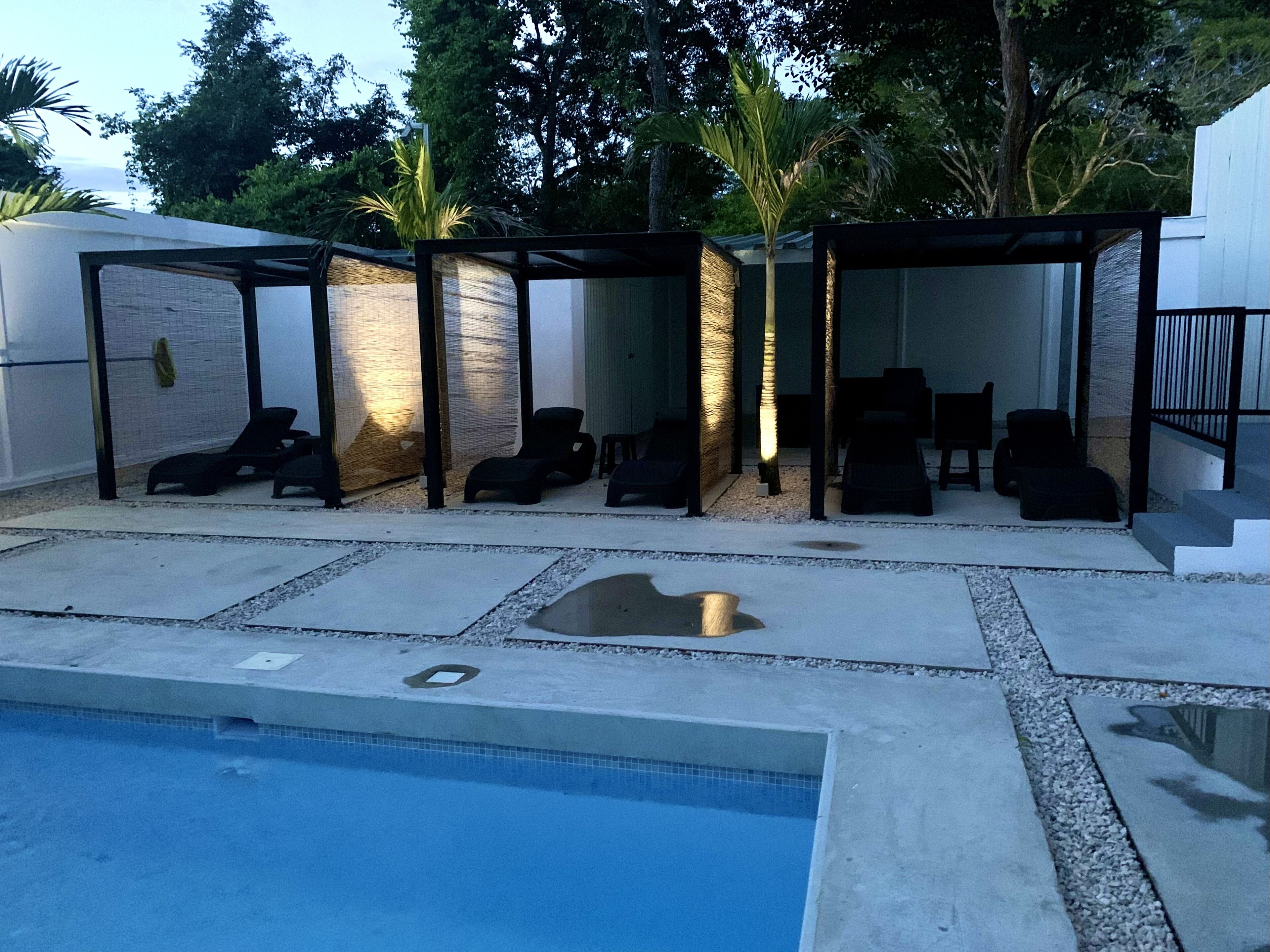 Zona junto a la piscina con sillones de descanso y un espacio de estar cubierto.