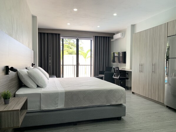A modern hotel room with a large bed, a desk with a chair, a television, and a wardrobe. - Whitestone Parkview Tamarindo 1 king bed studio w/kitchen 7min walk to the beach (Tamarindo)