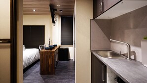 Une chambre d’hôtel compacte comprenant un coin cuisine, un lit et un petit espace repas.