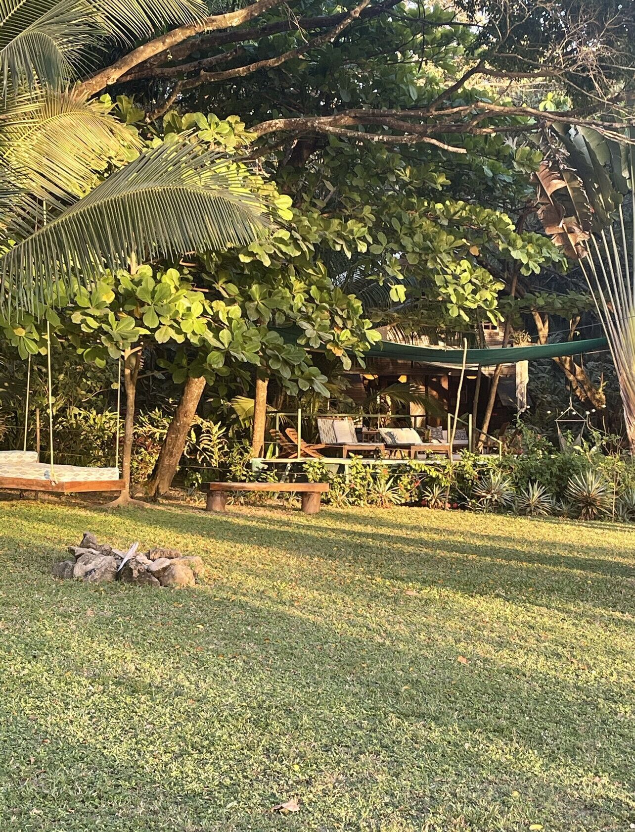 Un jardín con una hamaca, un banco y un columpio.