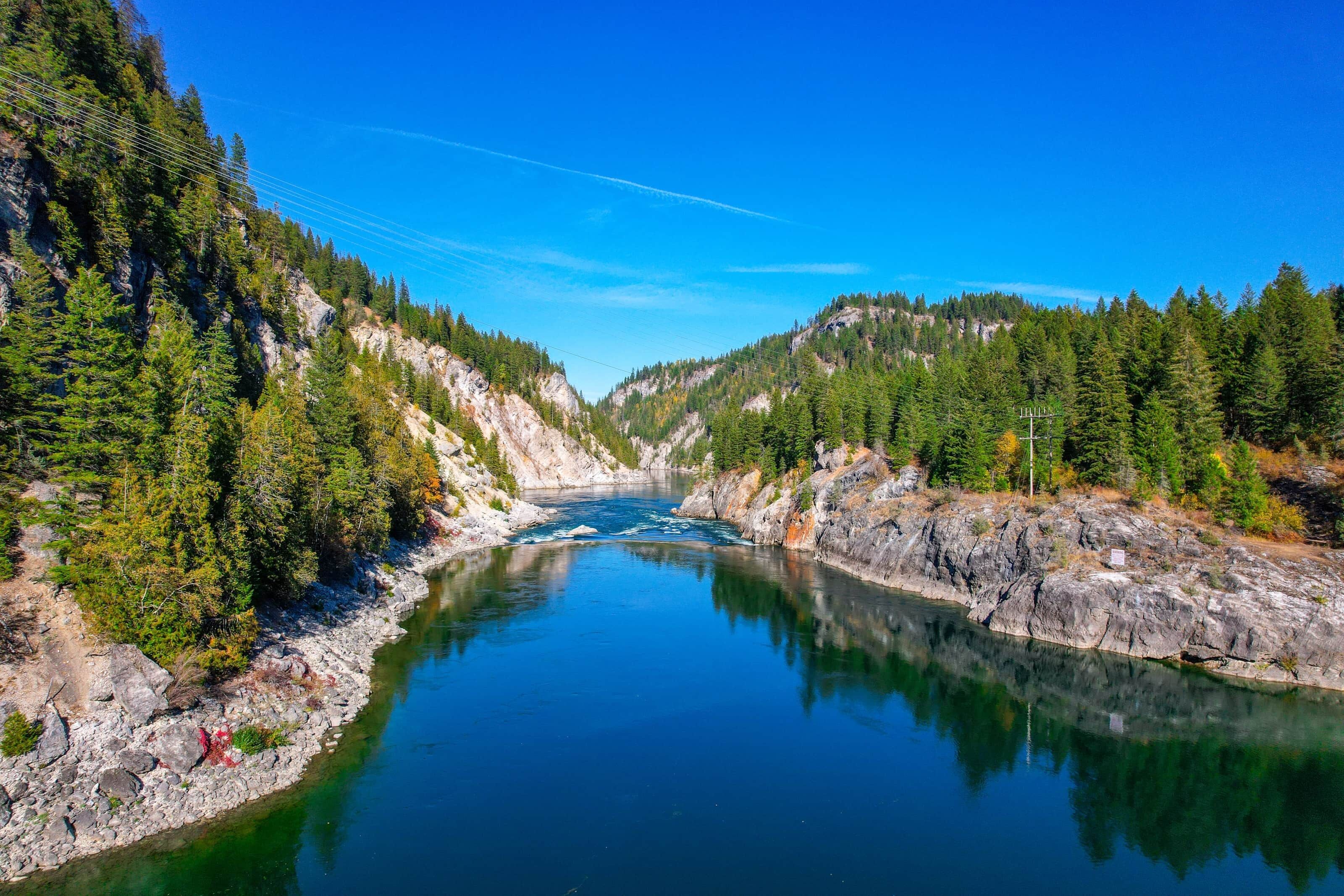 Une rivière bordée de montagnes boisées et de terrains rocheux.