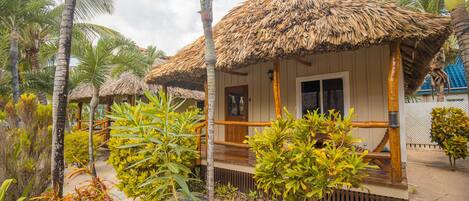A beachfront resort with thatched-roof huts, palm trees, and a sandy beach.