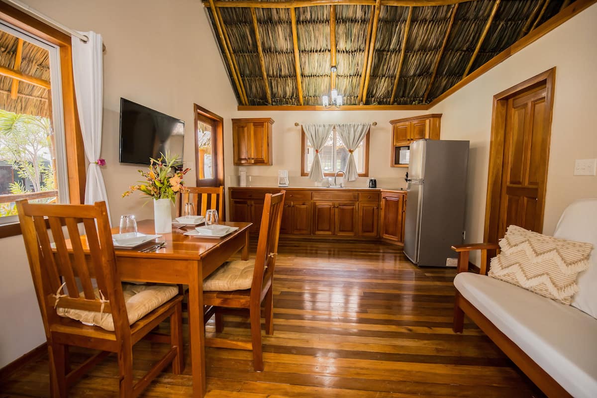 Een functionele keuken met houten kastjes, een koelkast en een zithoek met een tafel en stoelen.