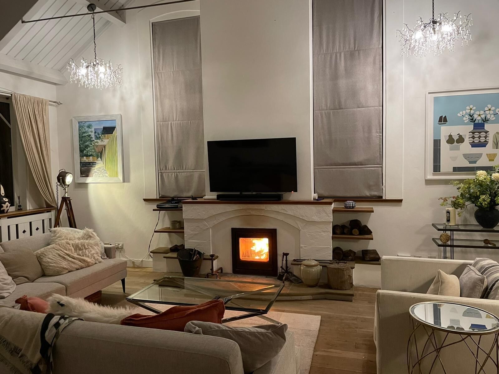 A living room with a fireplace, a television, and a chandelier.