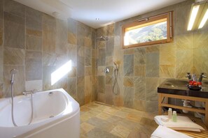 A bathroom with a bathtub, shower, and sink, featuring stone tiles and a window with a view. - Chalet, view mountain, terrace, balcony, fireplace or stove, parking, tv, 162m², Les 2 Alpes (Les Deux Alpes)