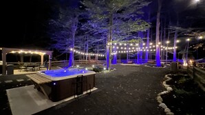 Un área de hidromasaje al aire libre con luces colgantes y una pérgola.