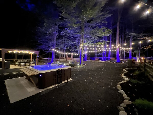An outdoor hot tub area with string lights and a pergola.