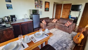 Un espacio habitable compacto con kitchenette, comedor y sofá con cojines decorativos.