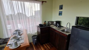Cocina compacta con una mesa de comedor preparada para cuatro personas, cafetera, tostadora y refrigerador.