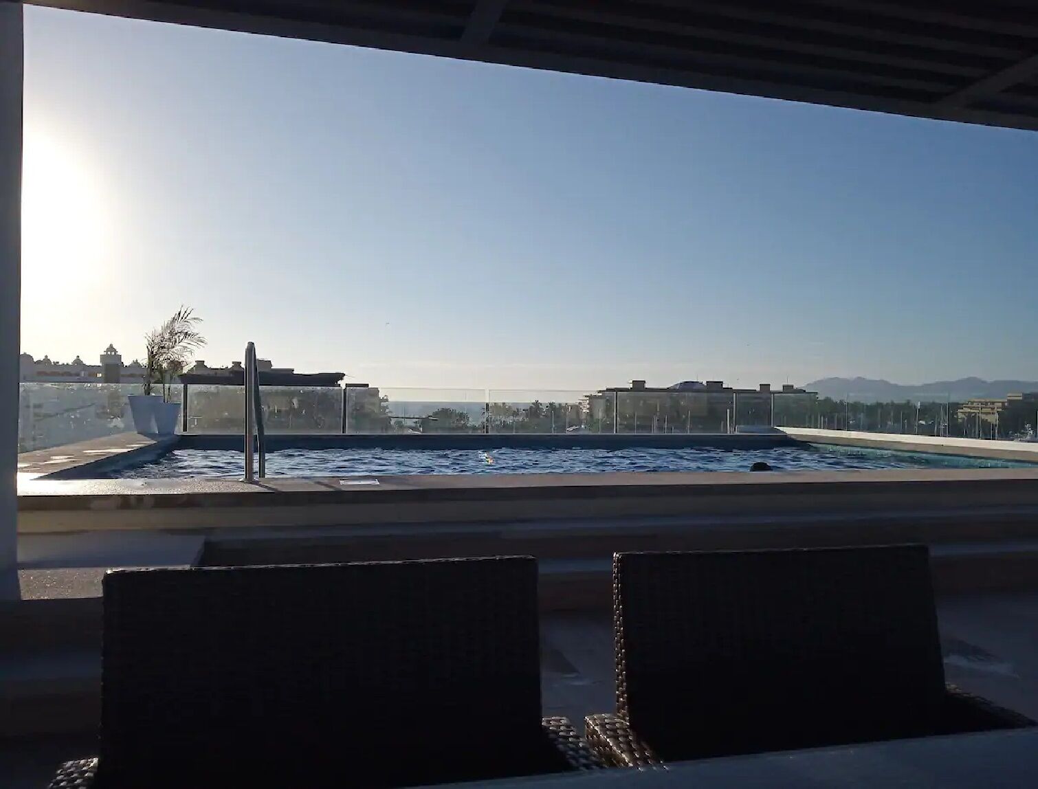 A rooftop pool with a clear view of the cityscape and mountains in the distance.