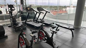 A gym with cardio machines, a bench, and a view of the city through large windows. - FRACCIONAMIENTO NAUTICO by TRVL2HM (Nuevo Nayarit)