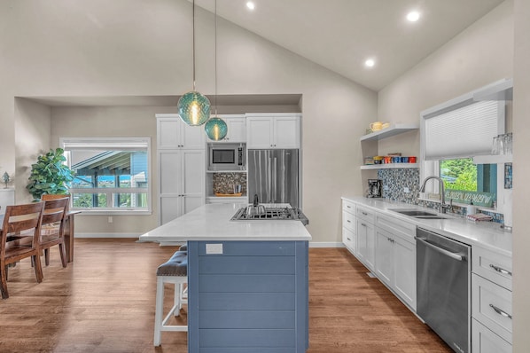 Enjoy cooking in this well-equipped kitchen with a large island, sink, and stainless steel appliances.
