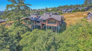 A house with a deck, surrounded by trees and other houses. - Incredible Ocean/Esturary Views, Large Covered Deck, Community Pool and Hot Tub (Pacific City)