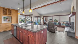 A spacious kitchen with a large island, wooden cabinets, and pendant lighting. - Incredible Ocean/Esturary Views, Large Covered Deck, Community Pool and Hot Tub (Pacific City)