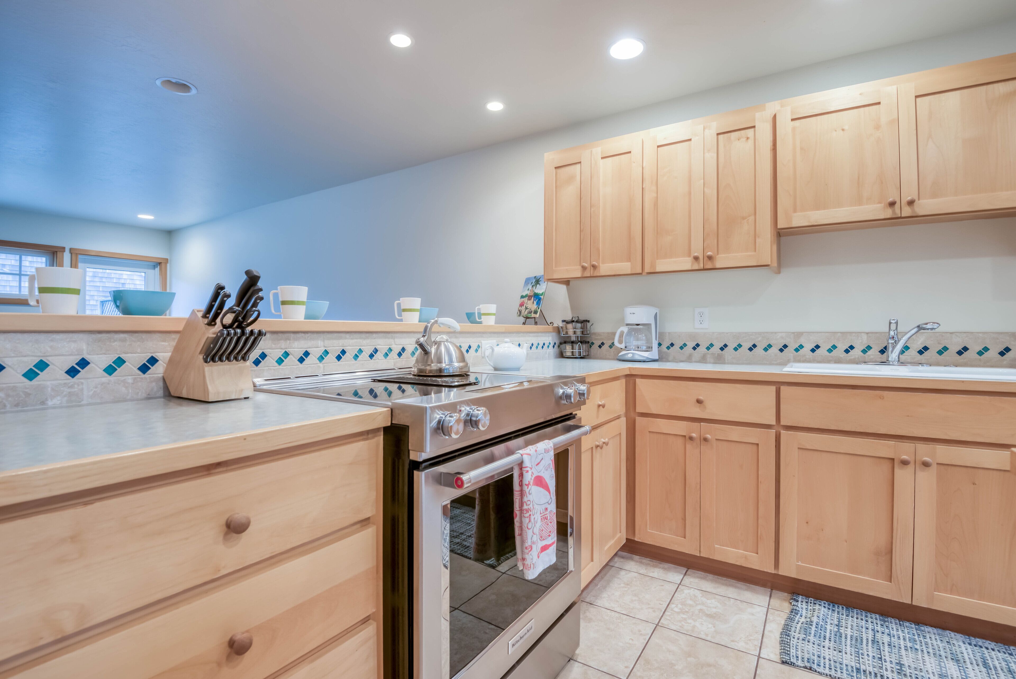 A modern kitchen with wooden cabinets, a stainless steel stove, and a tiled backsplash.