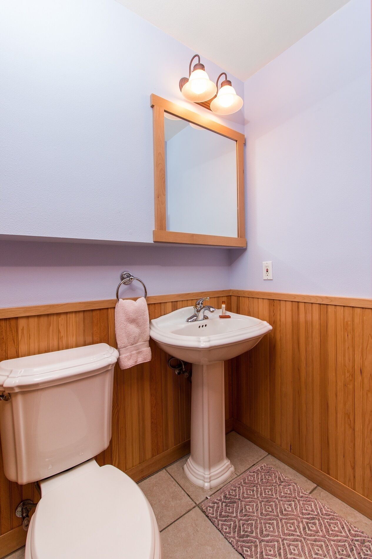 A bathroom with a toilet, sink, and mirror.