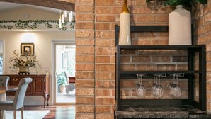 A brick wall with a shelf holding wine glasses and a vase.