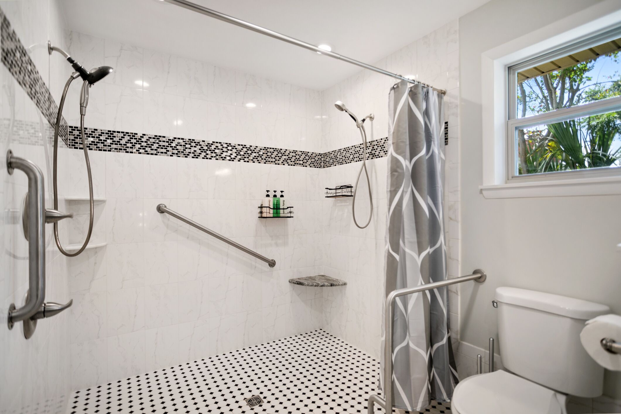 Une salle de bain moderne équipée d’une douche, de toilettes et d’une fenêtre qui laisse entrer la lumière naturelle.