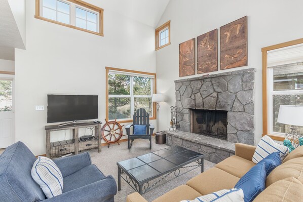 A spacious living room with a stone fireplace, a television, and comfortable seating.