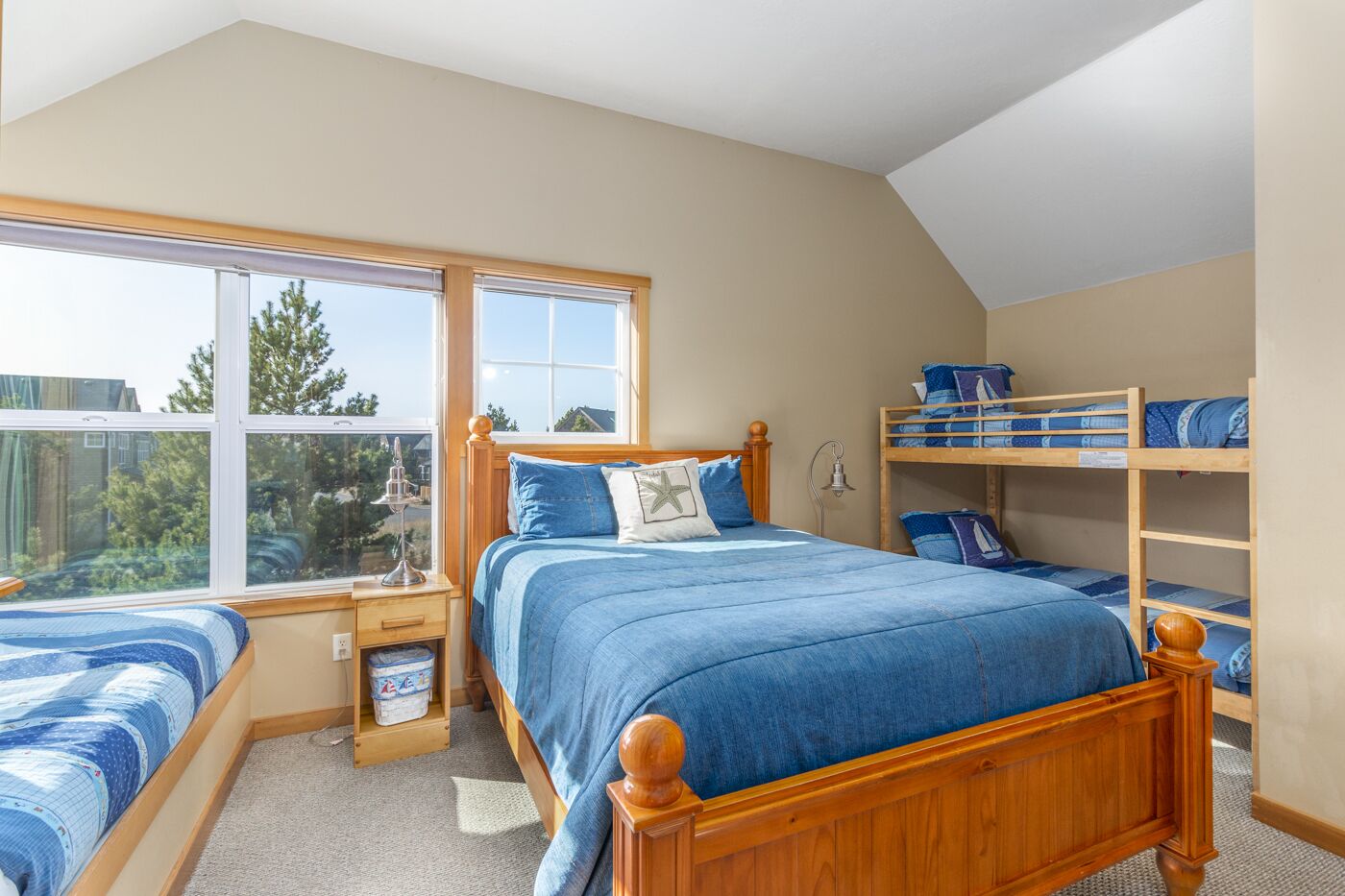 A bedroom with a large window, a bunk bed, a bedside table, and a nightstand.