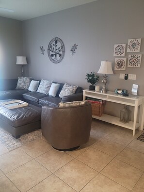 A living room with a sofa, ottoman, and a console table with decorative items.