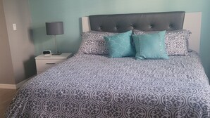 A bedroom with a bed, a nightstand, a lamp, and a painting on the wall. - Affordable, One floor, Spacious Condo, Conveniently Located 15 minutes to Disney (Kissimmee)