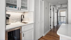 A modern kitchen with white cabinetry, a built-in oven, and a countertop with a coffee maker.