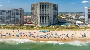 A beachfront hotel with multiple high-rise buildings, a sandy beach, and a view of the ocean.