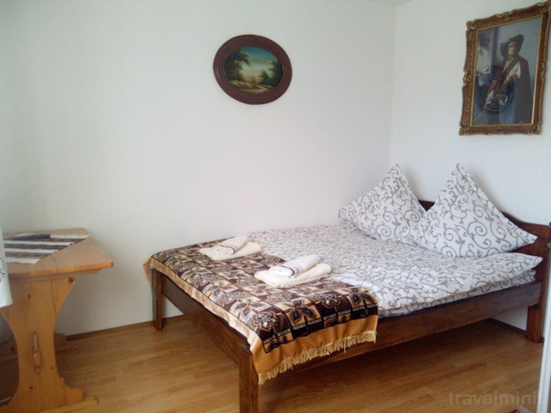 A single bed with patterned bedding, a small bedside table, and a framed picture on the wall.