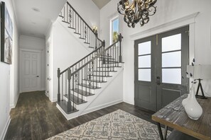 A staircase with black railings, a patterned rug, and a white vase on a table. - Sea of Dreams. Remodeled Lakefront 4 Bed, Heated Pool, Golf Cart and Bikes! (Destin)