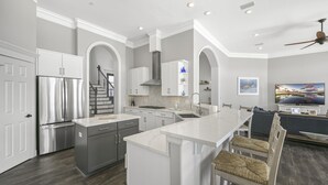 A modern kitchen with a central island, stainless steel appliances, and a dining area with a TV.