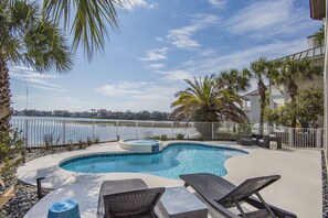 A swimming pool with lounge chairs, a hot tub, and a view of the water. - Sea of Dreams. Remodeled Lakefront 4 Bed, Heated Pool, Golf Cart and Bikes! (Destin)