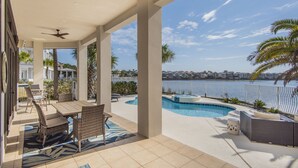 A covered outdoor area with a pool, seating, and a view of the water.