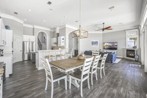 A spacious kitchen with a dining area, white cabinetry, and a large wooden table. - Sea of Dreams. Remodeled Lakefront 4 Bed, Heated Pool, Golf Cart and Bikes! (Destin)