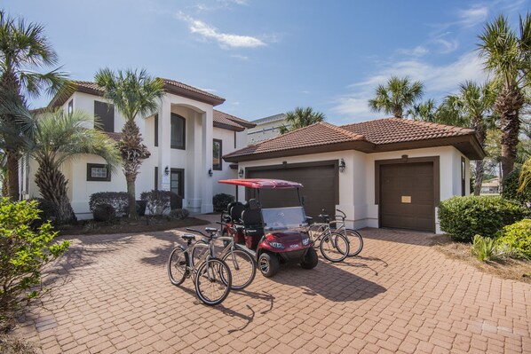 A residential property with a paved driveway, a golf cart, and bicycles. - Sea of Dreams. Remodeled Lakefront 4 Bed, Heated Pool, Golf Cart and Bikes! (Destin)