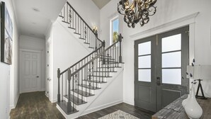 A staircase with black railings, a patterned rug, and a white vase on a table.