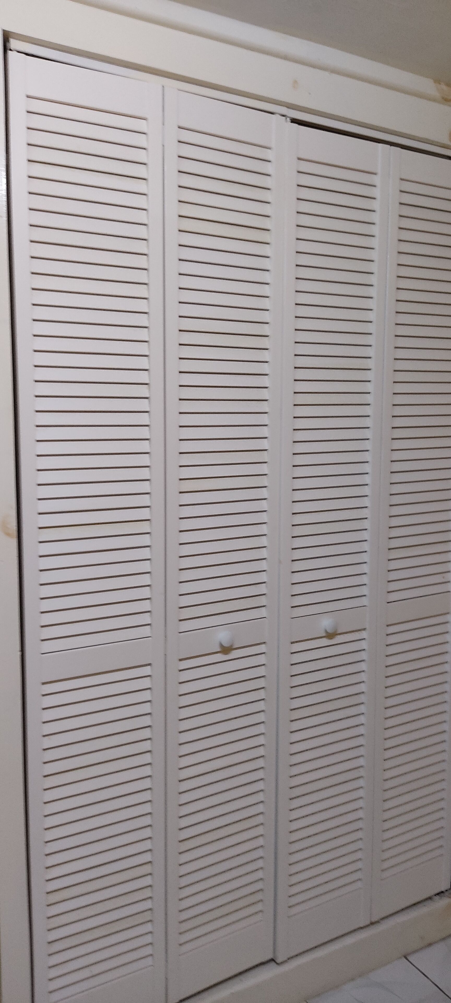 Ein weißer Schrank mit horizontalen Lamellen und zwei Griffen.