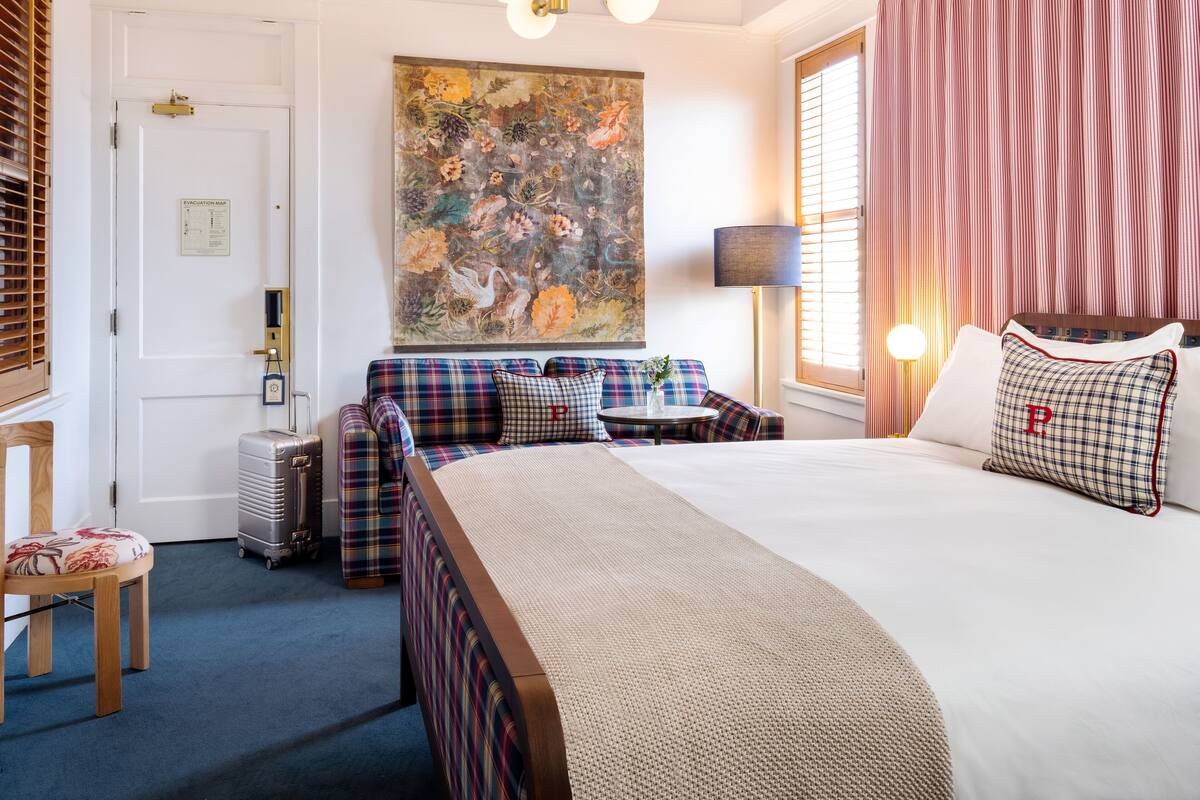 Ein Hotelzimmer mit einem großen Bett, einer Couch, einem kleinen Tisch und einem Gemälde an der Wand.