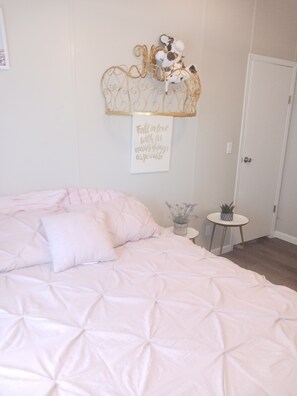 Cozy retreat with a large bed, decorative headboard, and a potted plant.