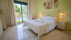 A bedroom with a bed, a nightstand, a chair, and a view of the outdoors. - La Almadraba apartment 204 (Manilva)