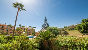 A resort with a pool, palm trees, and a clear blue sky. - La Almadraba apartment 204 (Manilva)