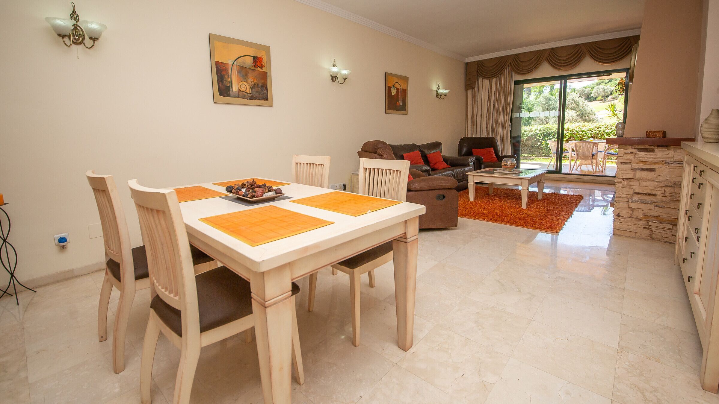 Un comedor con una mesa y sillas, un sofá y una mesita de centro en una habitación luminosa con vistas al exterior.