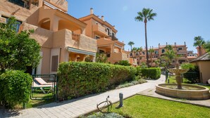 A courtyard with a fountain, a bike, and a poolside area. - La Almadraba apartment 204 (Manilva)
